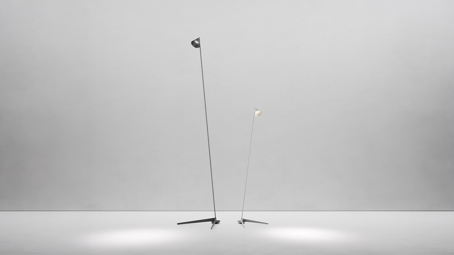 Due lampade da terra Artemide Vea con bracci neri sottili e paralumi conici su basi a treppiede, che proiettano fasci di luce sul pavimento