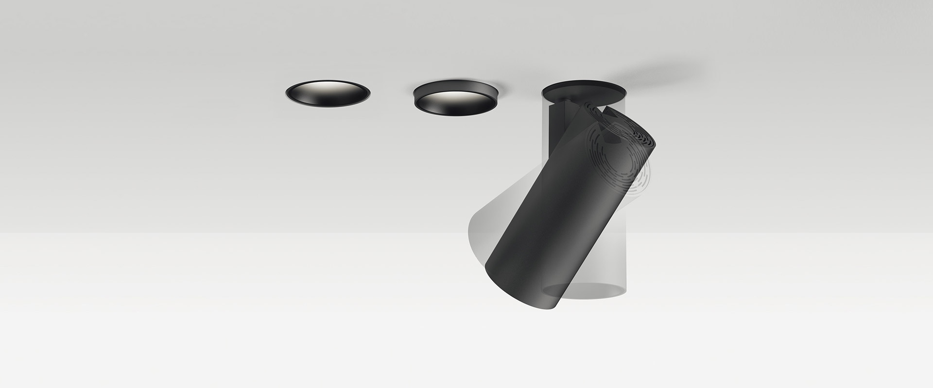 Mano che installa un faretto da incasso a soffitto Vector Recessed di Artemide, con corpo cilindrico nero a filo di un soffitto bianco