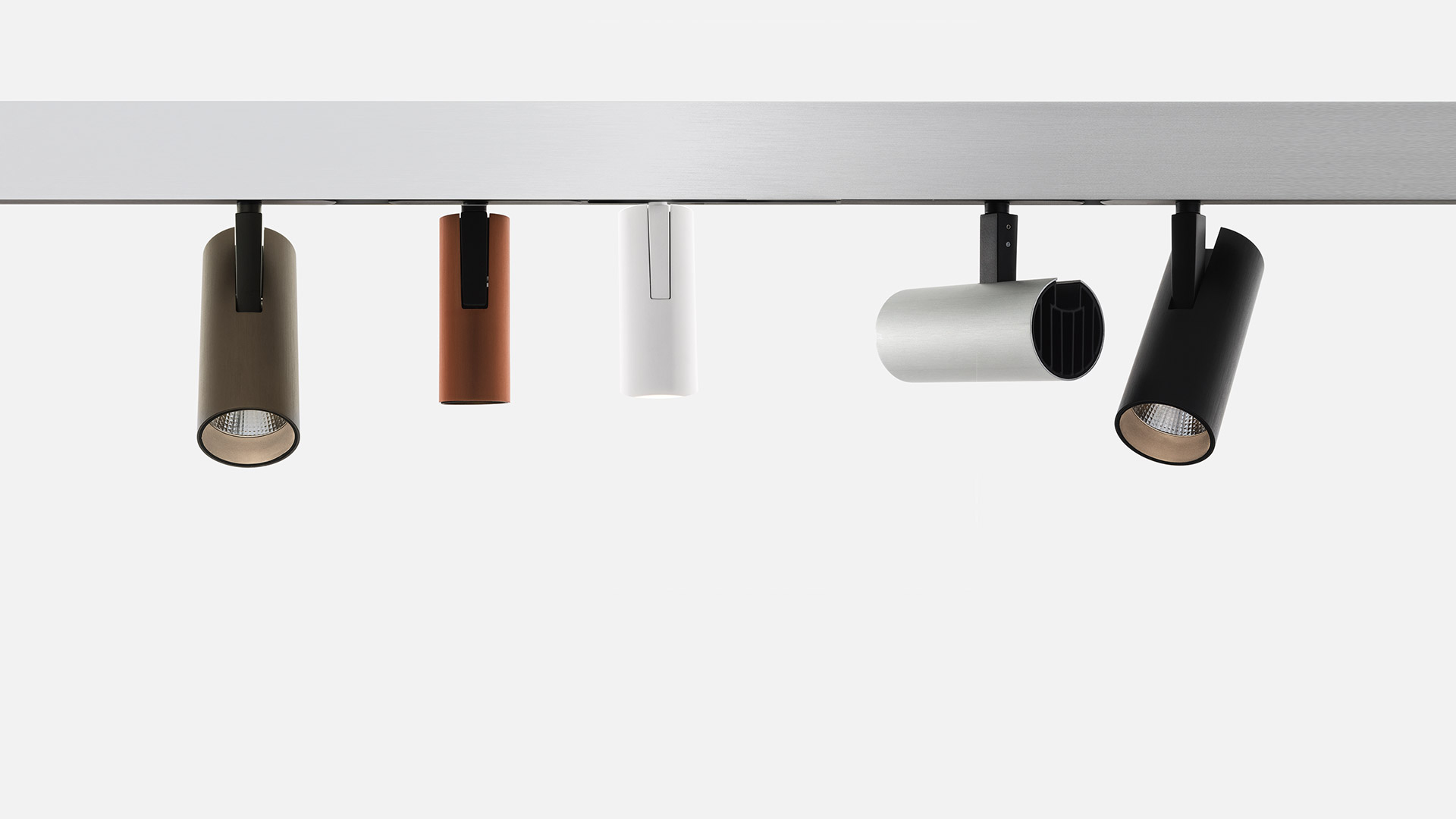 Cinque faretti da binario Artemide Vector in corpo cilindrico color oliva, rame, bianco, grigio chiaro e nero su binario magnetico