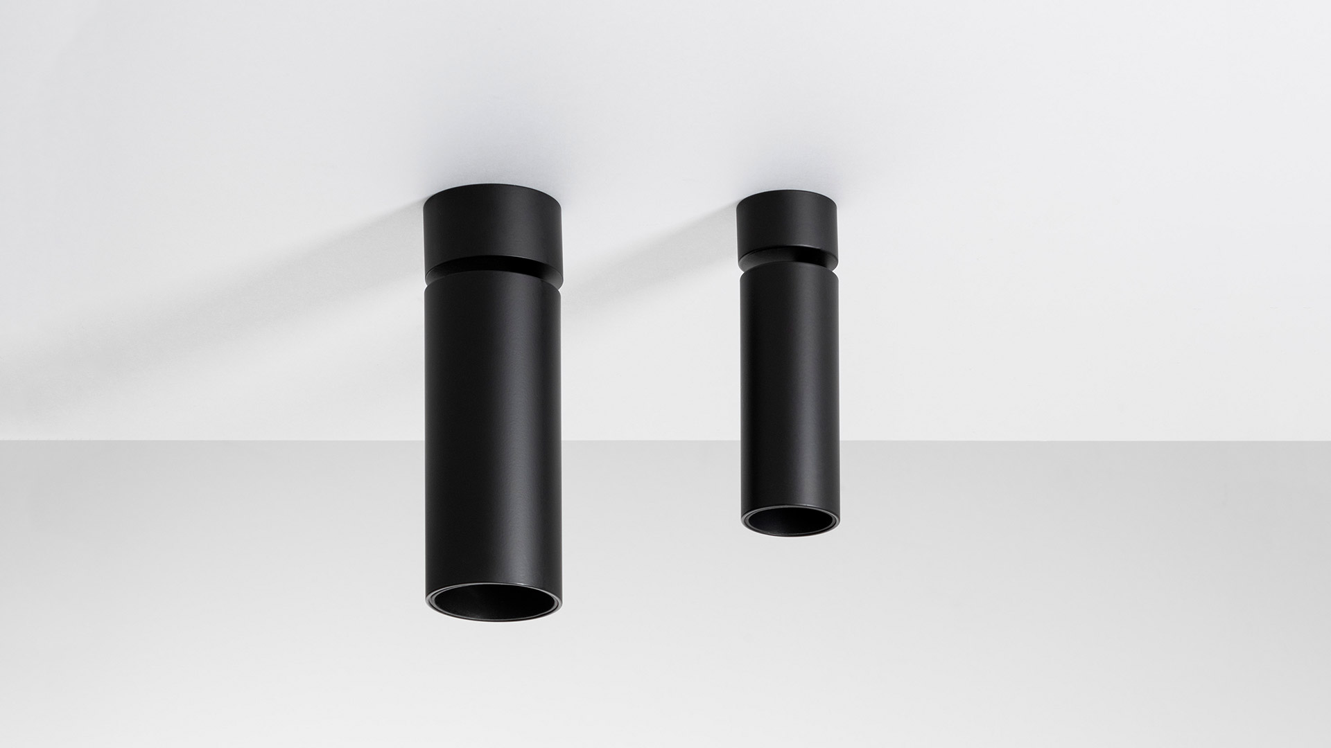 Two Artemide Vector Ceiling spotlights in matte black, cylindrical shape, surface-mounted on white ceiling