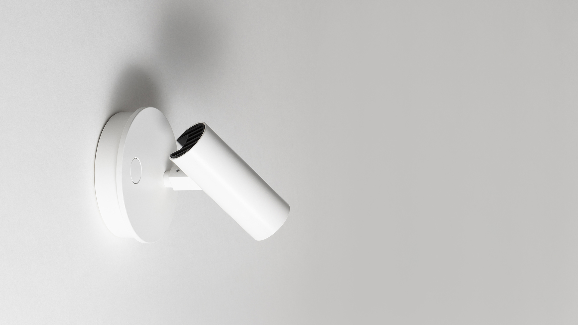 Artemide Vector Wall spotlight in white, wall-mounted adjustable cylindrical lamp head on circular base, angled downward
