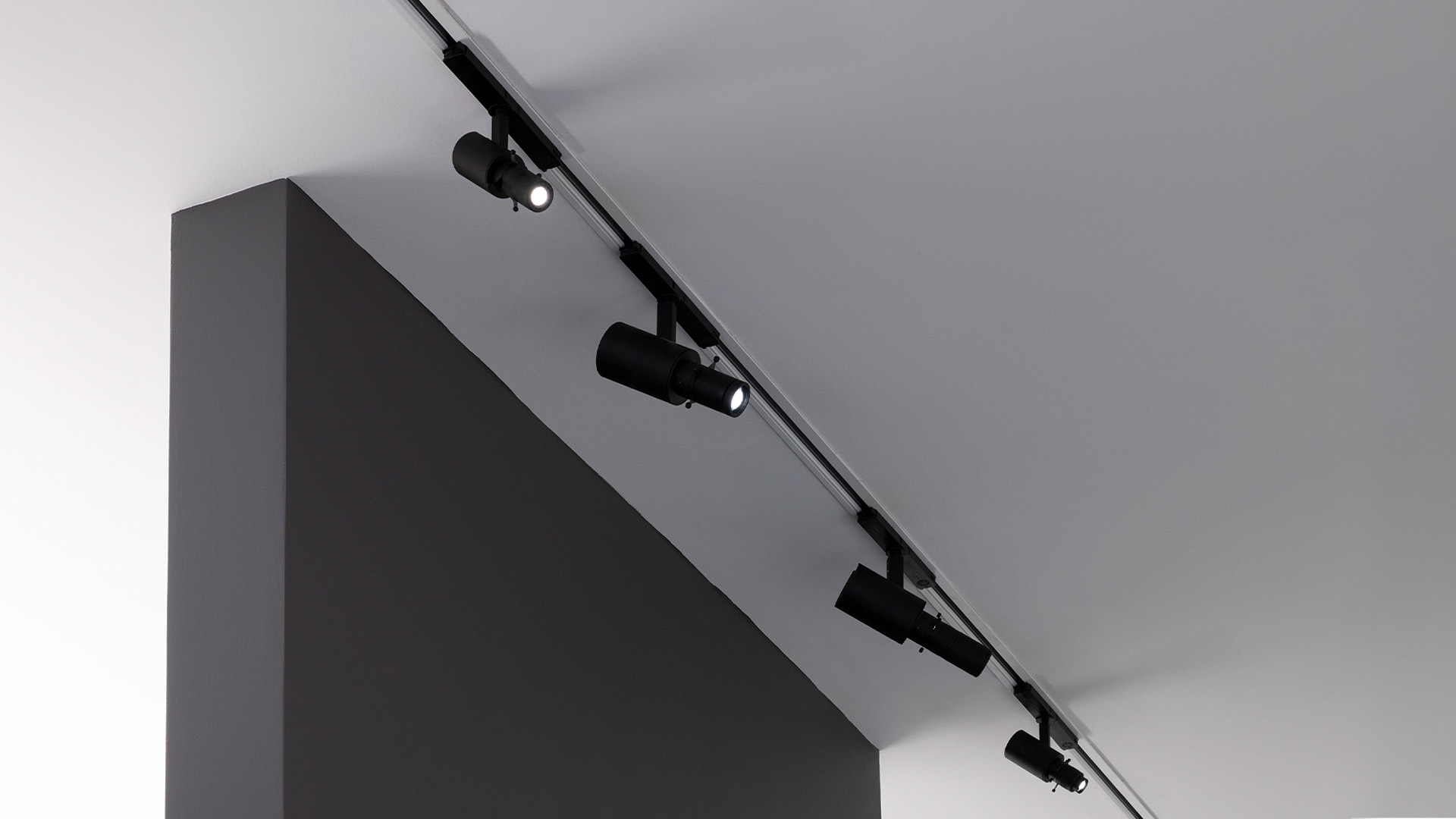 Multiple black Artemide Vector track spotlights mounted on a ceiling rail, directing focused beams of light in a gallery-like space