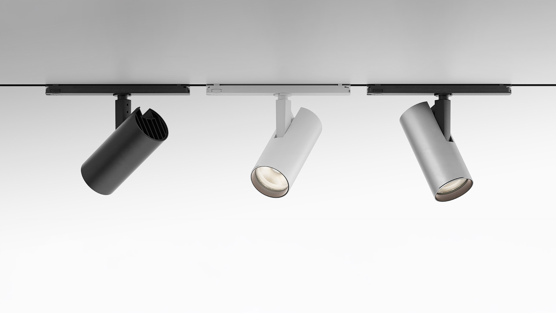 Tre faretti Artemide Vector Track 230V neri di dimensioni graduate montati su binario nero a soffitto, spenti