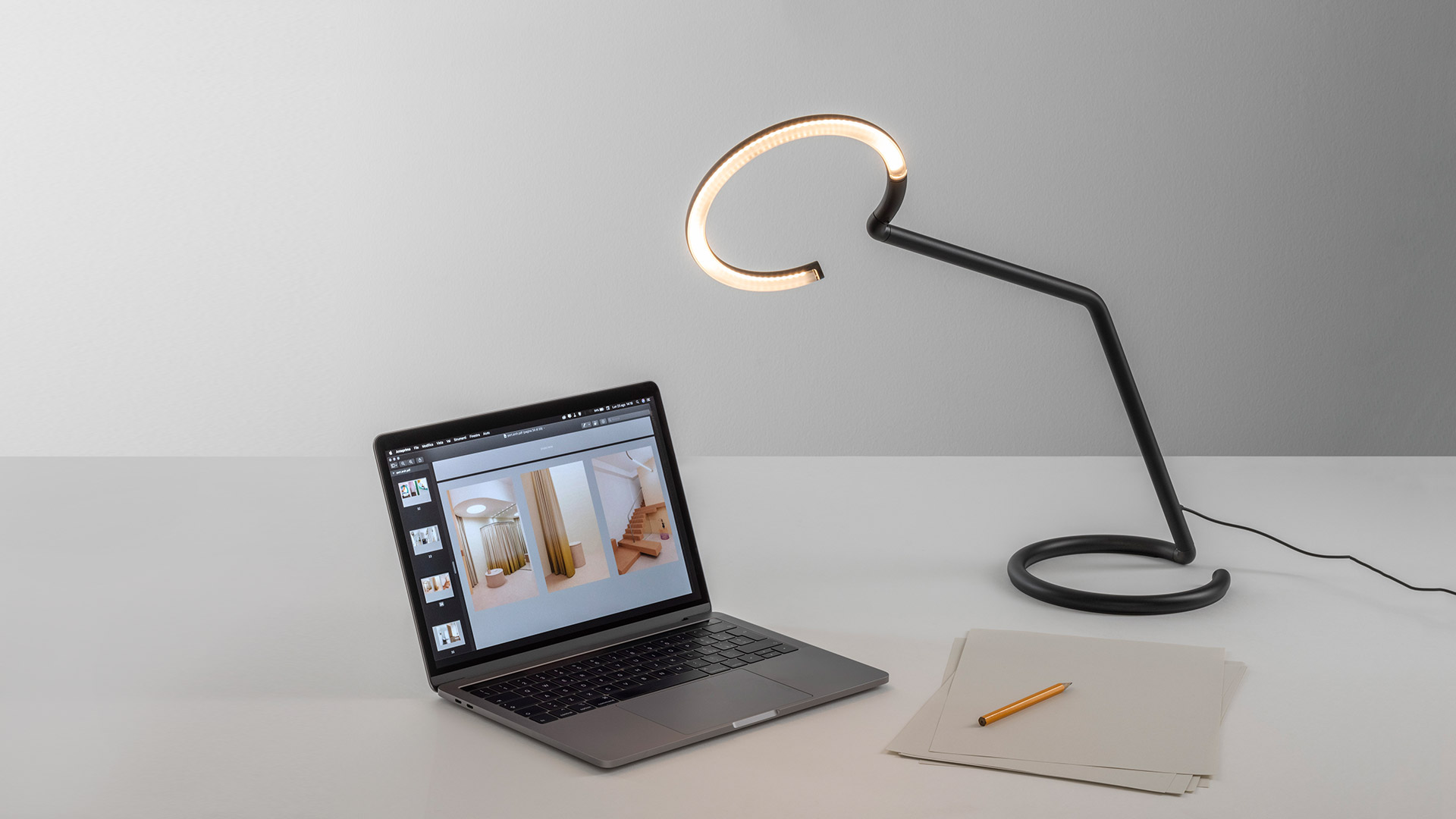 Artemide Vine Light black floor lamp with circular LED ring head, arching over a minimalist white desk in a modern workspace