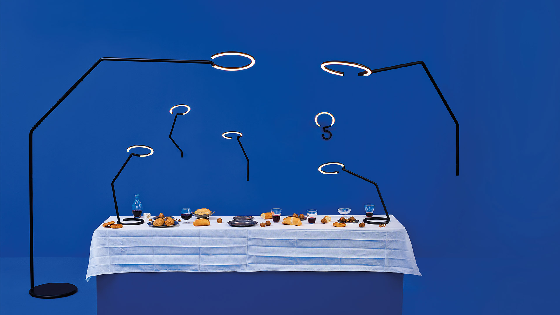 Hand adjusting the flexible black tubular arm of the Artemide Vine Light lamp, demonstrating its bendable and positionable design