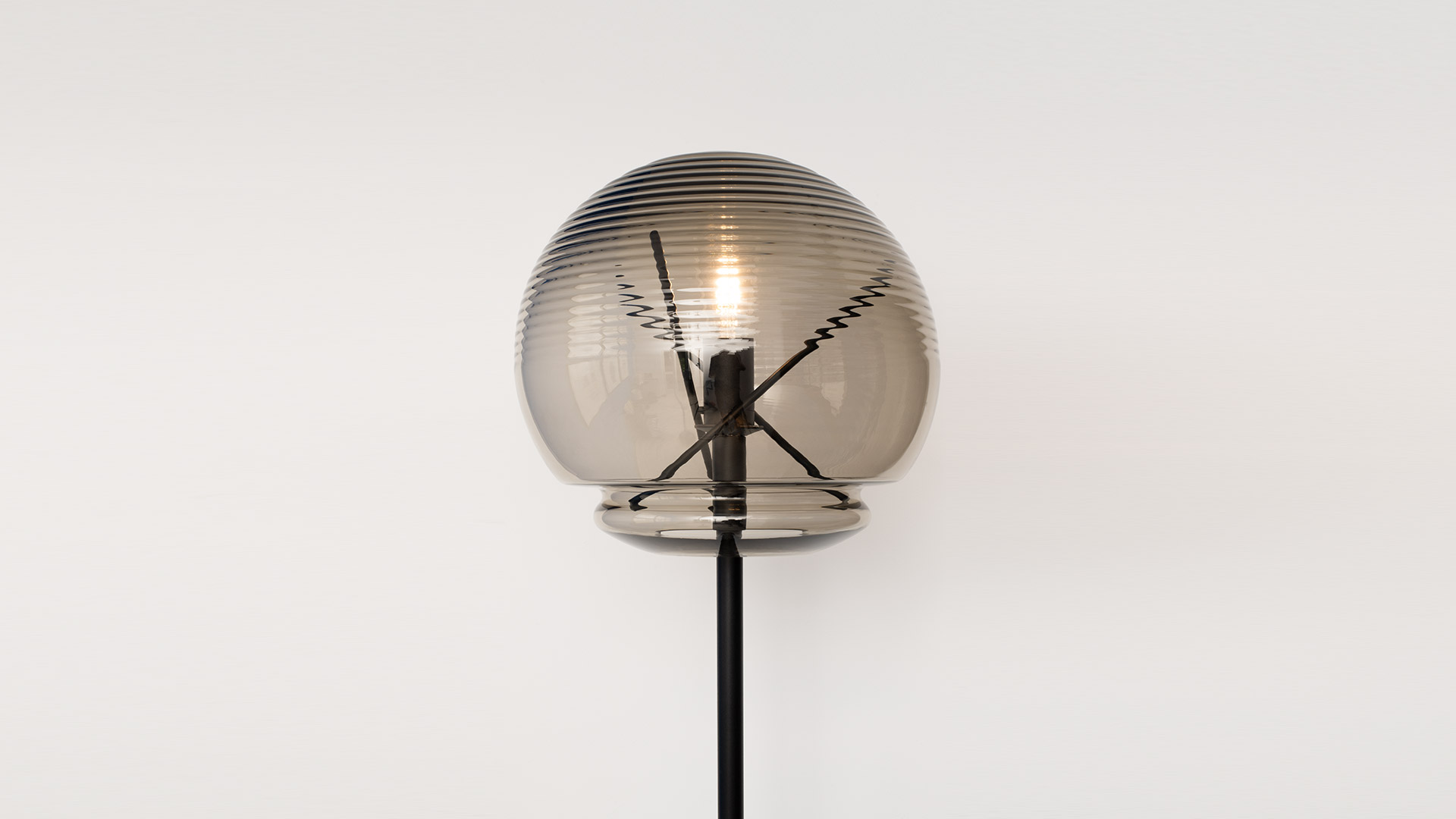 Lampada da terra Artemide Vitruvio: alto fusto in ottone con base rotonda, paralume a globo in vetro trasparente con portalampada geometrico in ottone a vista