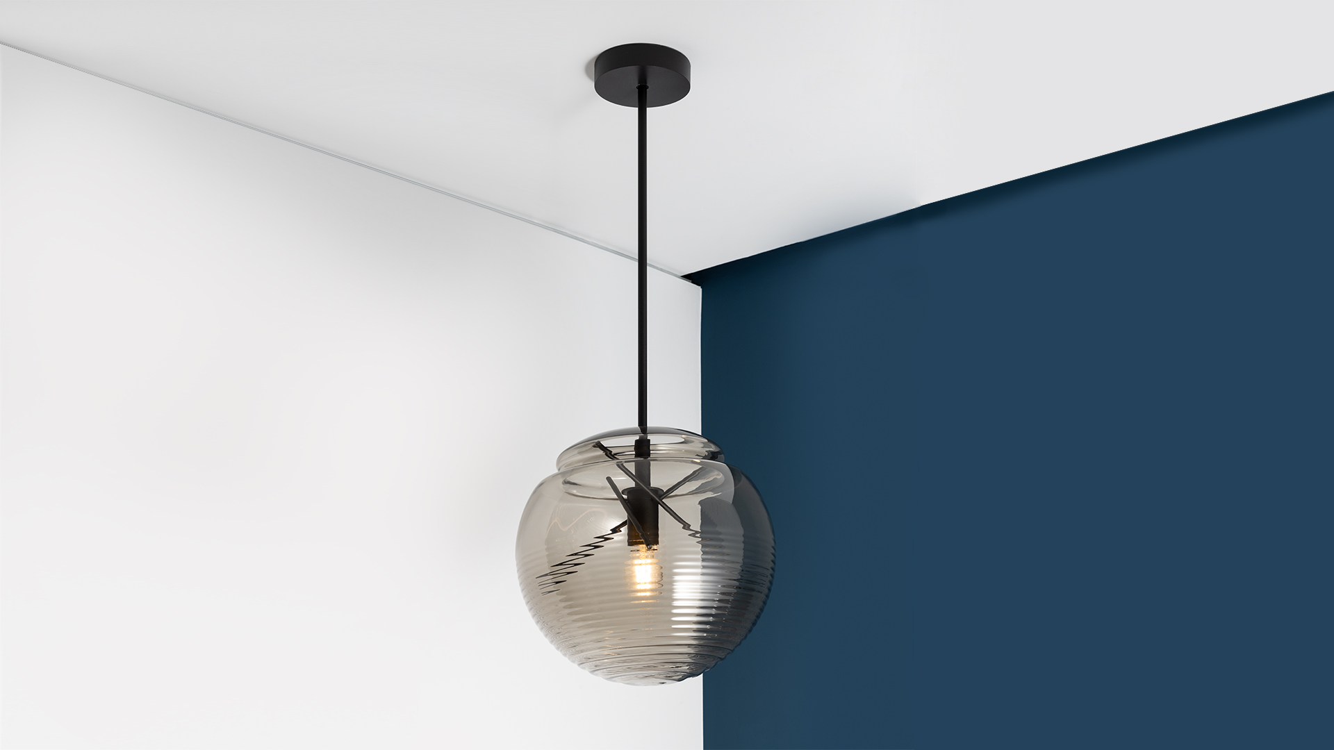 Lampada a sospensione Artemide Vitruvio con sfera in vetro rigato fumé e stelo in metallo nero, appesa a soffitto bianco