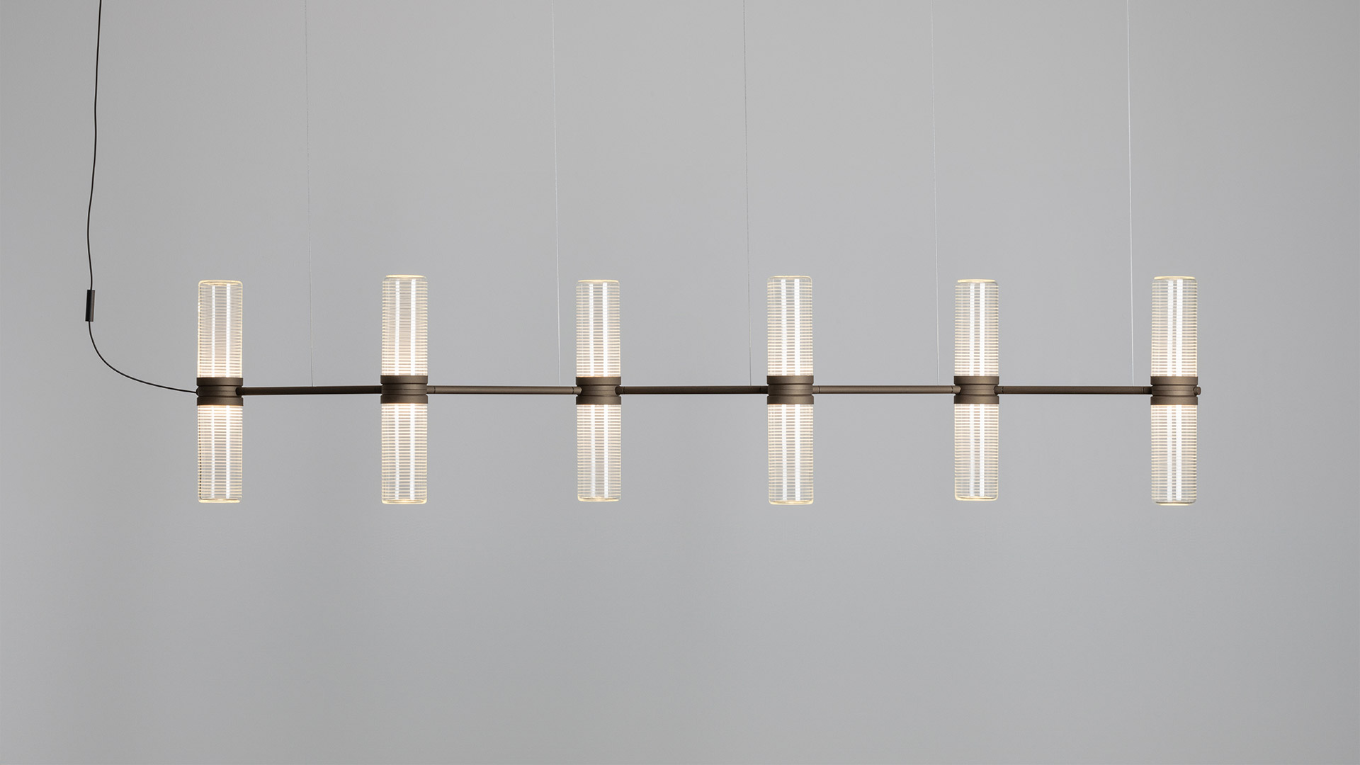 Lampada a sospensione Artemide Zephyr: barra metallica nera orizzontale con 8 diffusori cilindrici in vetro satinato disposti in coppie