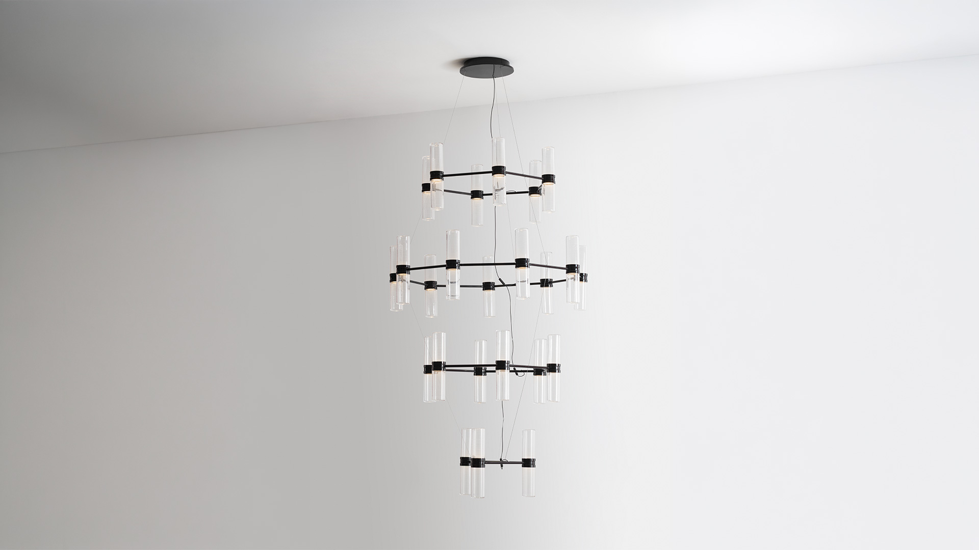 Lampada a sospensione Zephyr di Artemide con barra in rame e diffusori tubolari verticali sopra un tavolo da pranzo in un interno moderno con piante tropicali